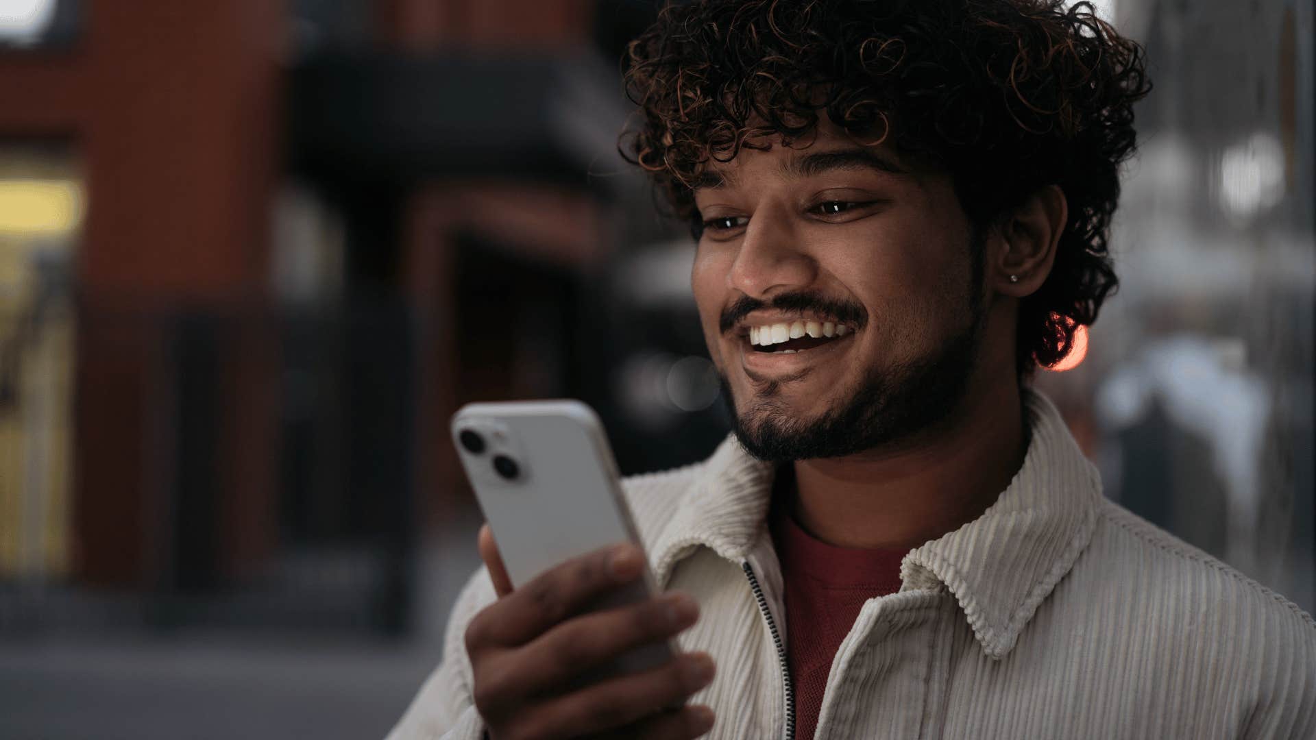 man smiling down at his phone