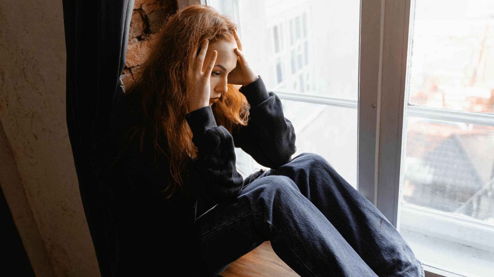 stressed young woman sitting near a window