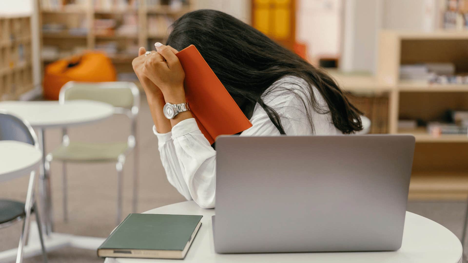 woman hiding her face in book