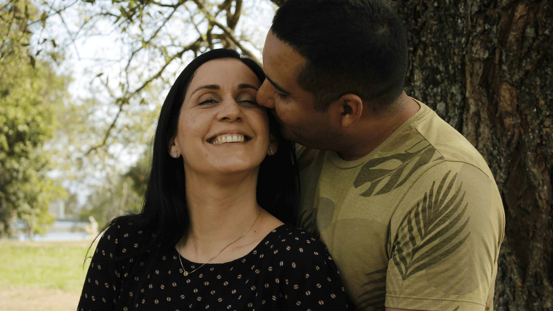 man hugging woman close and kissing temple