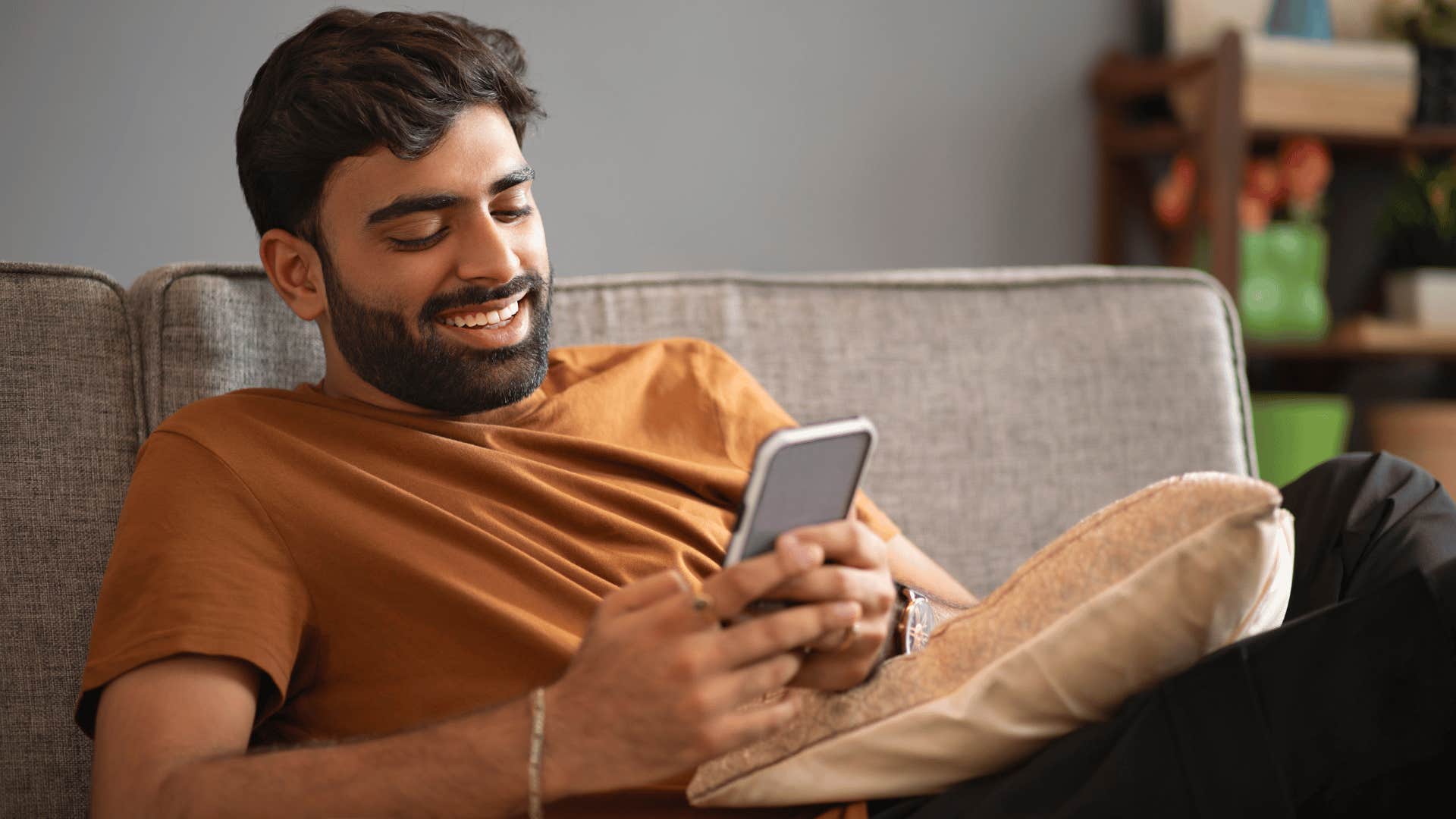 man relaxing on the couch using his phone