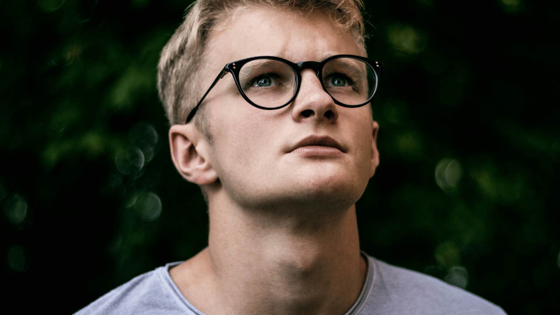 young man in glasses gazing up