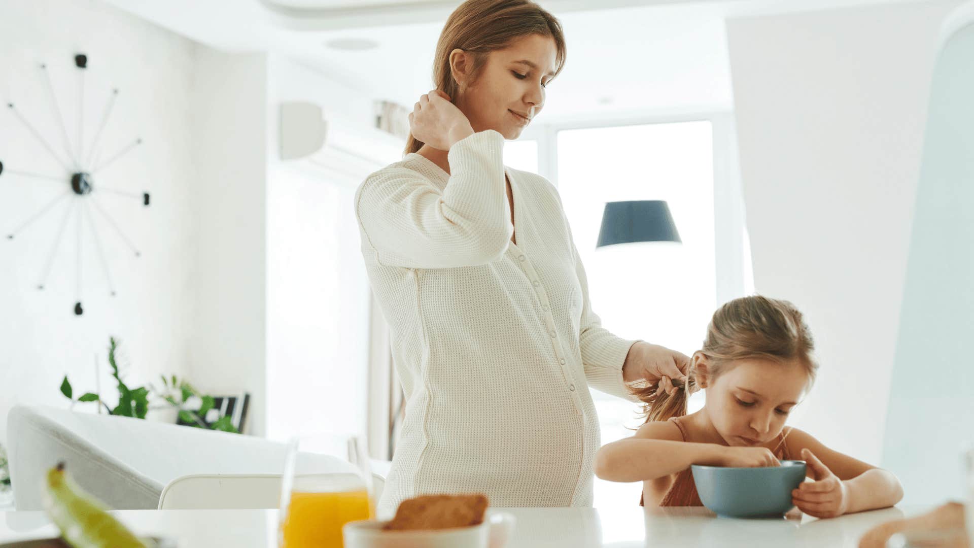 pregnant woman braiding young girls hair