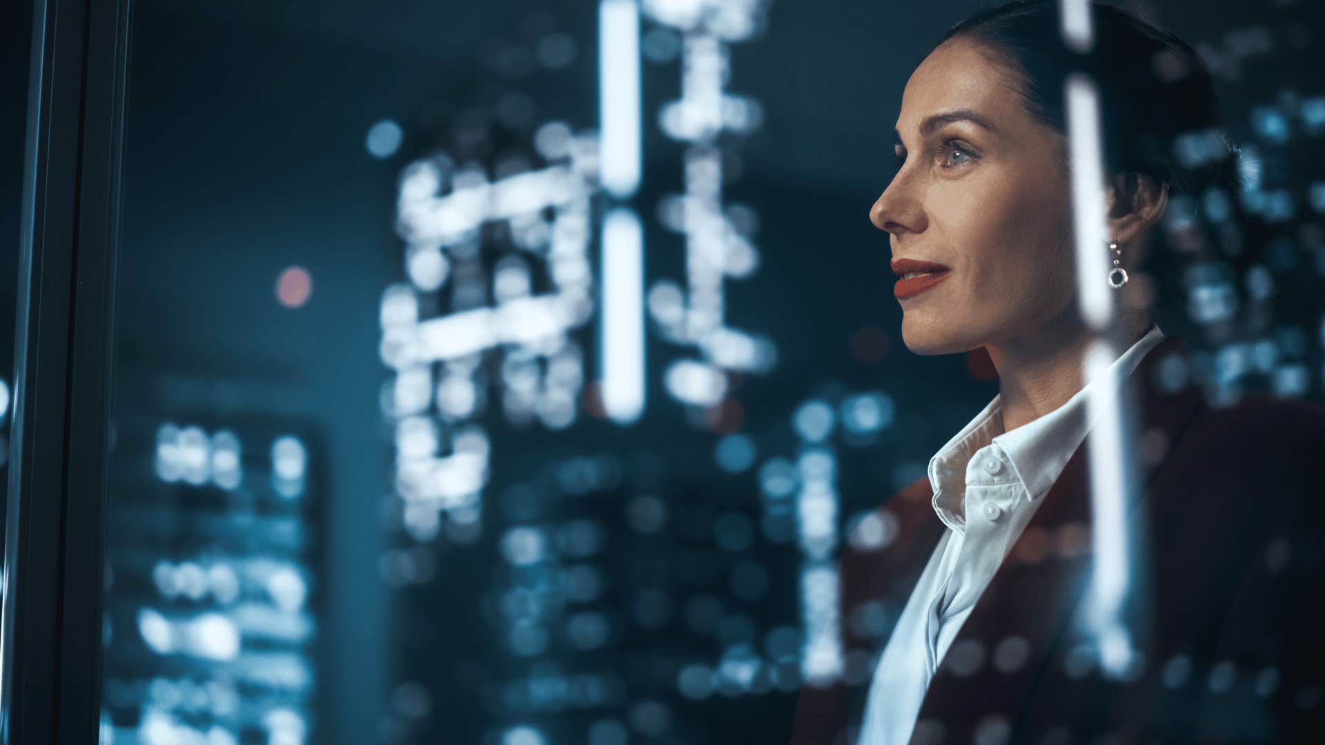 successful woman looking out at the city at night