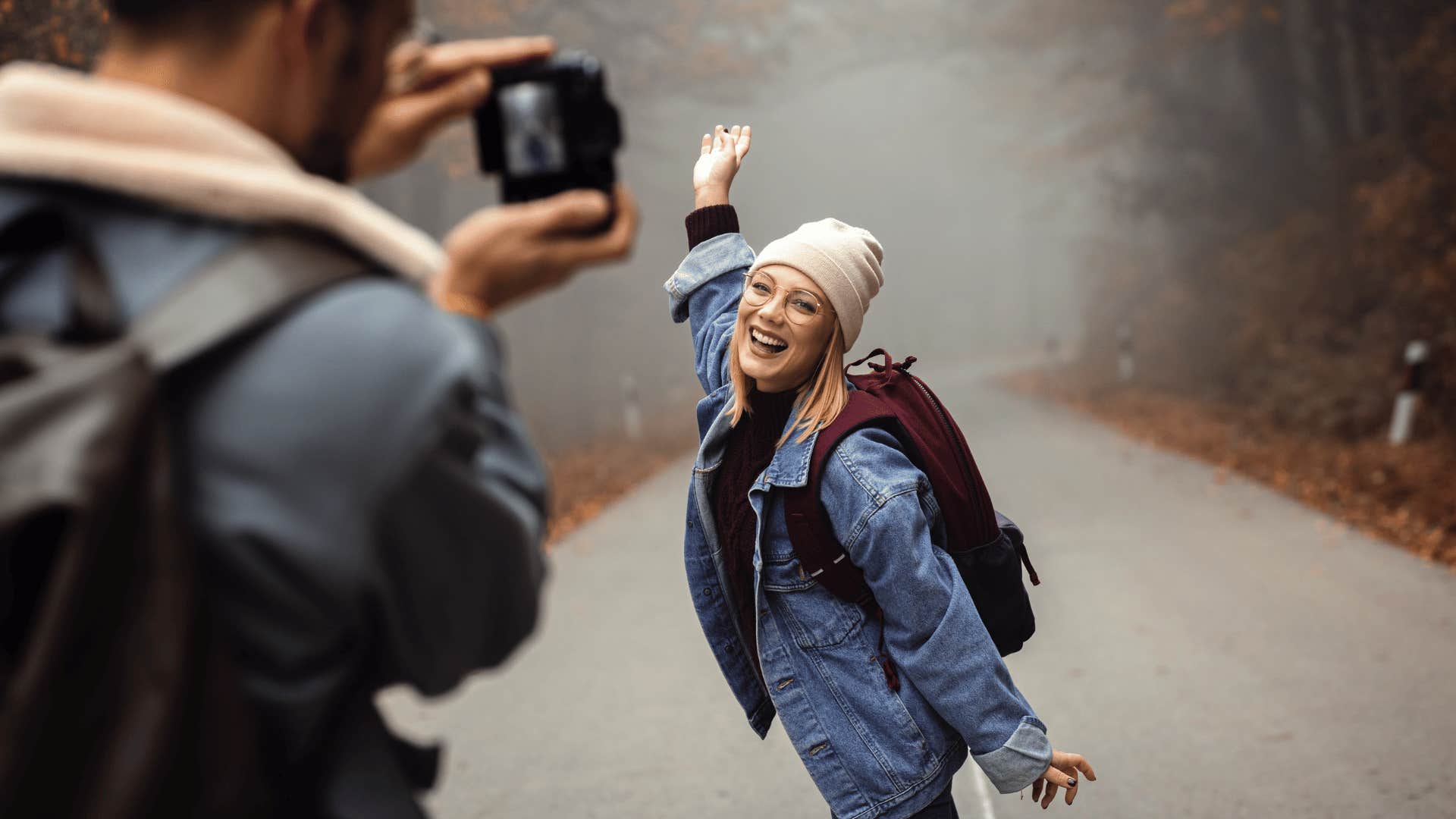 man taking a photo of a woman on a foggy forest road