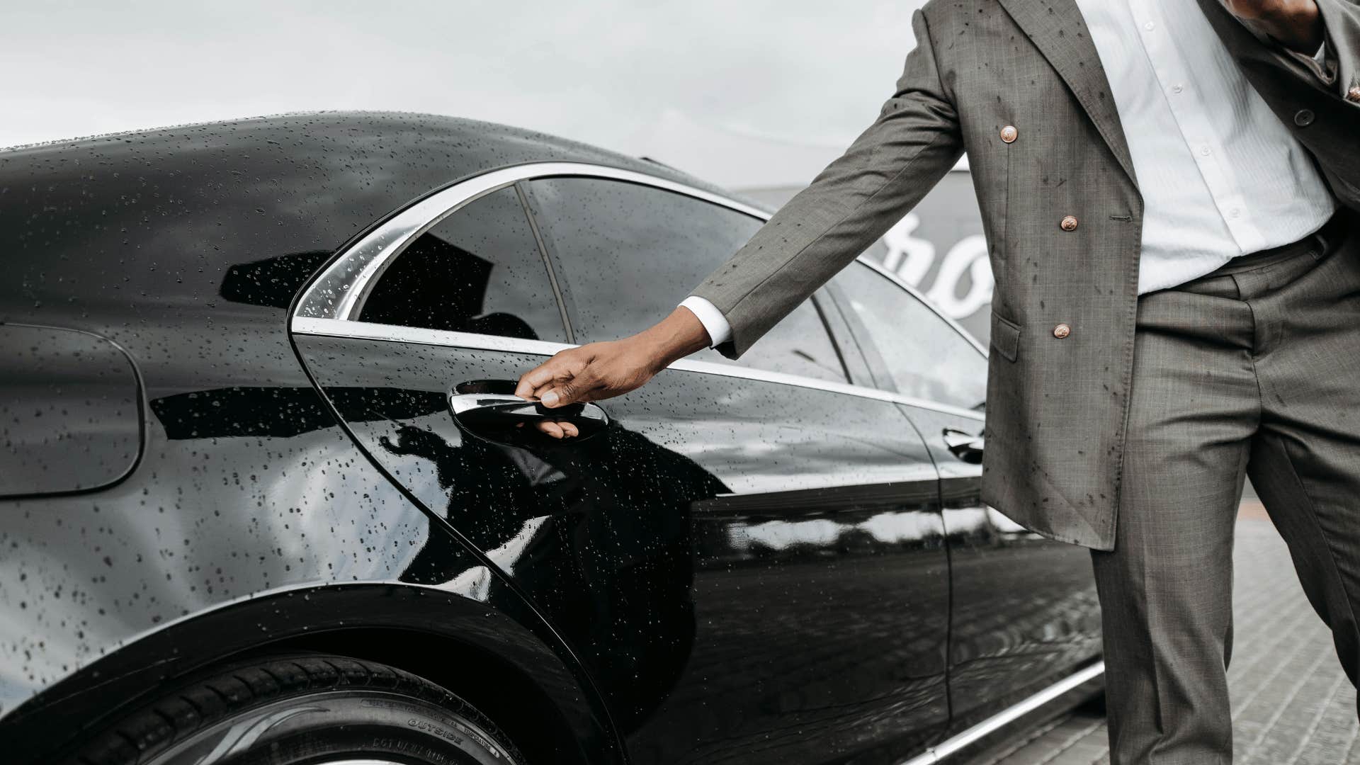 man holding an umbrella and opening car door