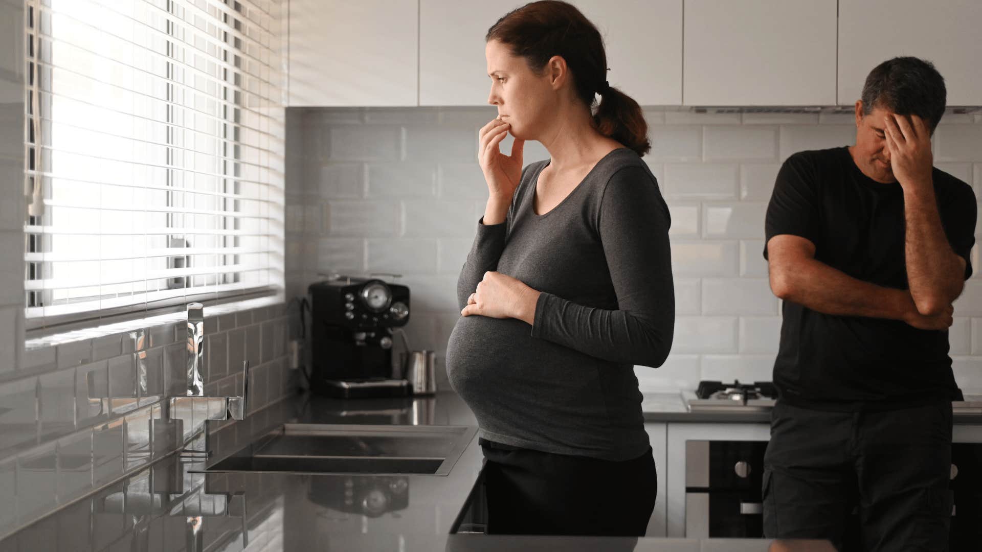 pregnant woman and frustrated man standing in the kitchen