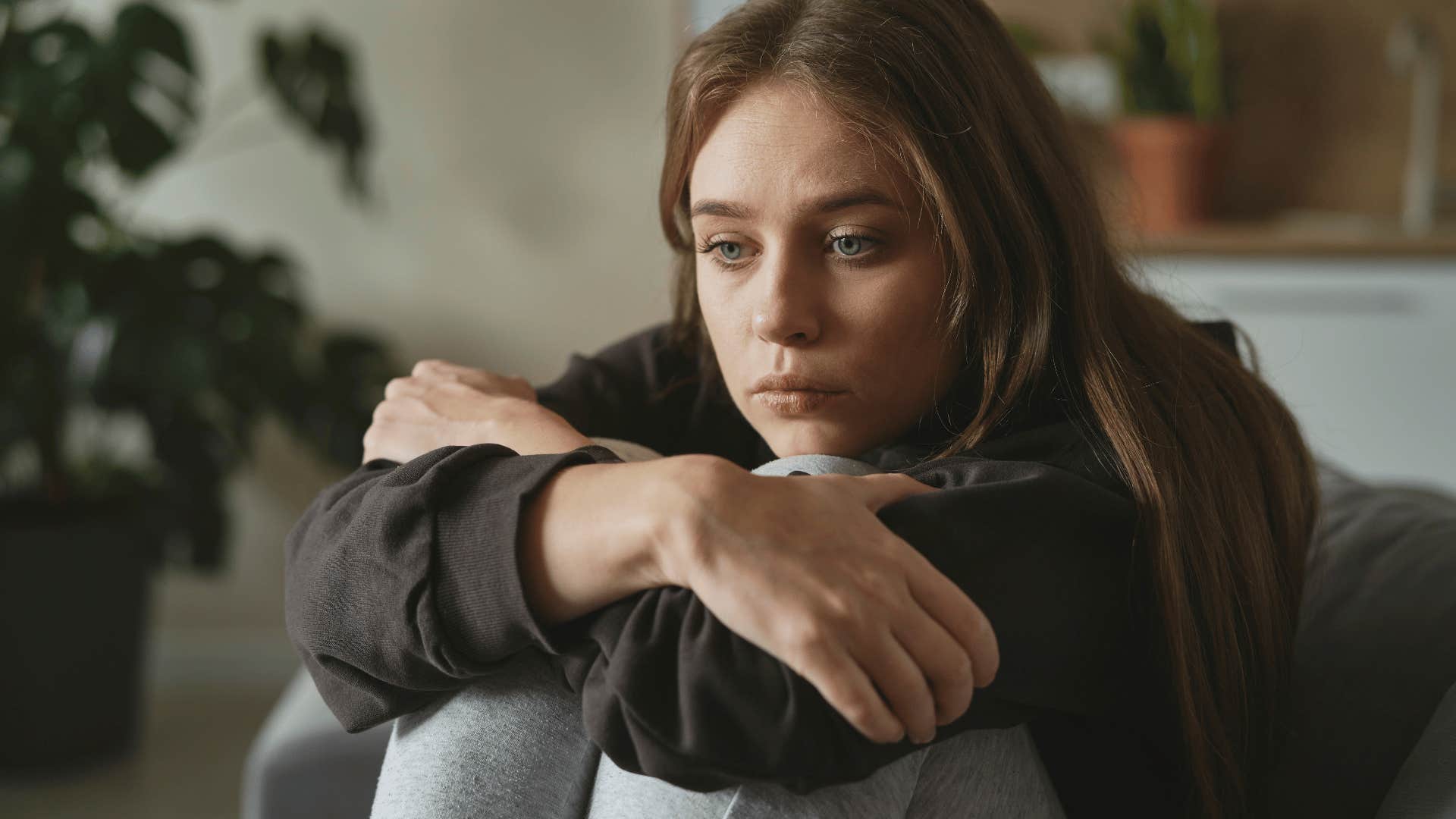 sad young woman hugging her knees to her chest