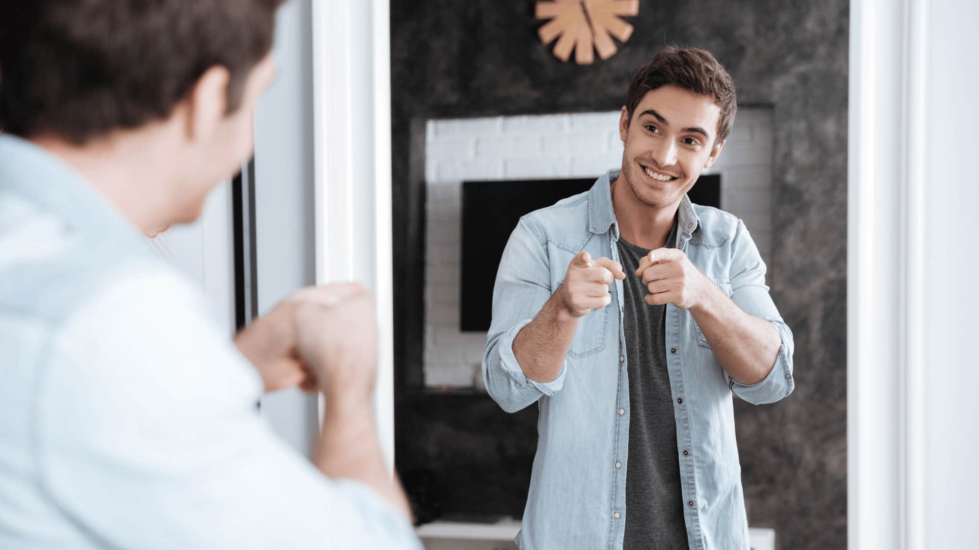 young man pointing fingers at his reflection