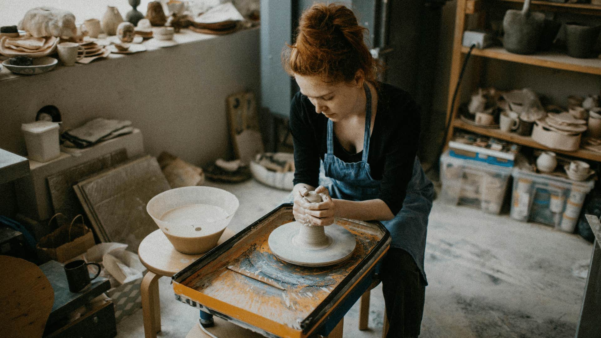 young woman in a pottery studio molding clay