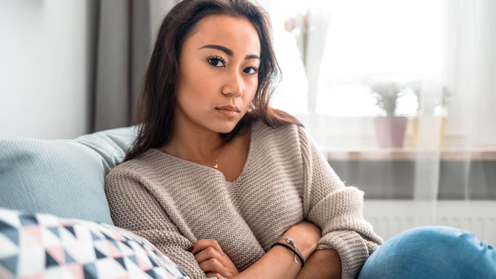 Woman looking upset sitting on her bed. 