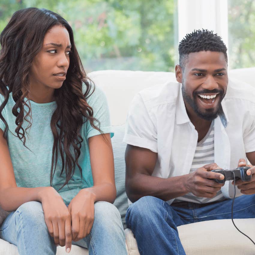 annoyed young woman next to man playing games