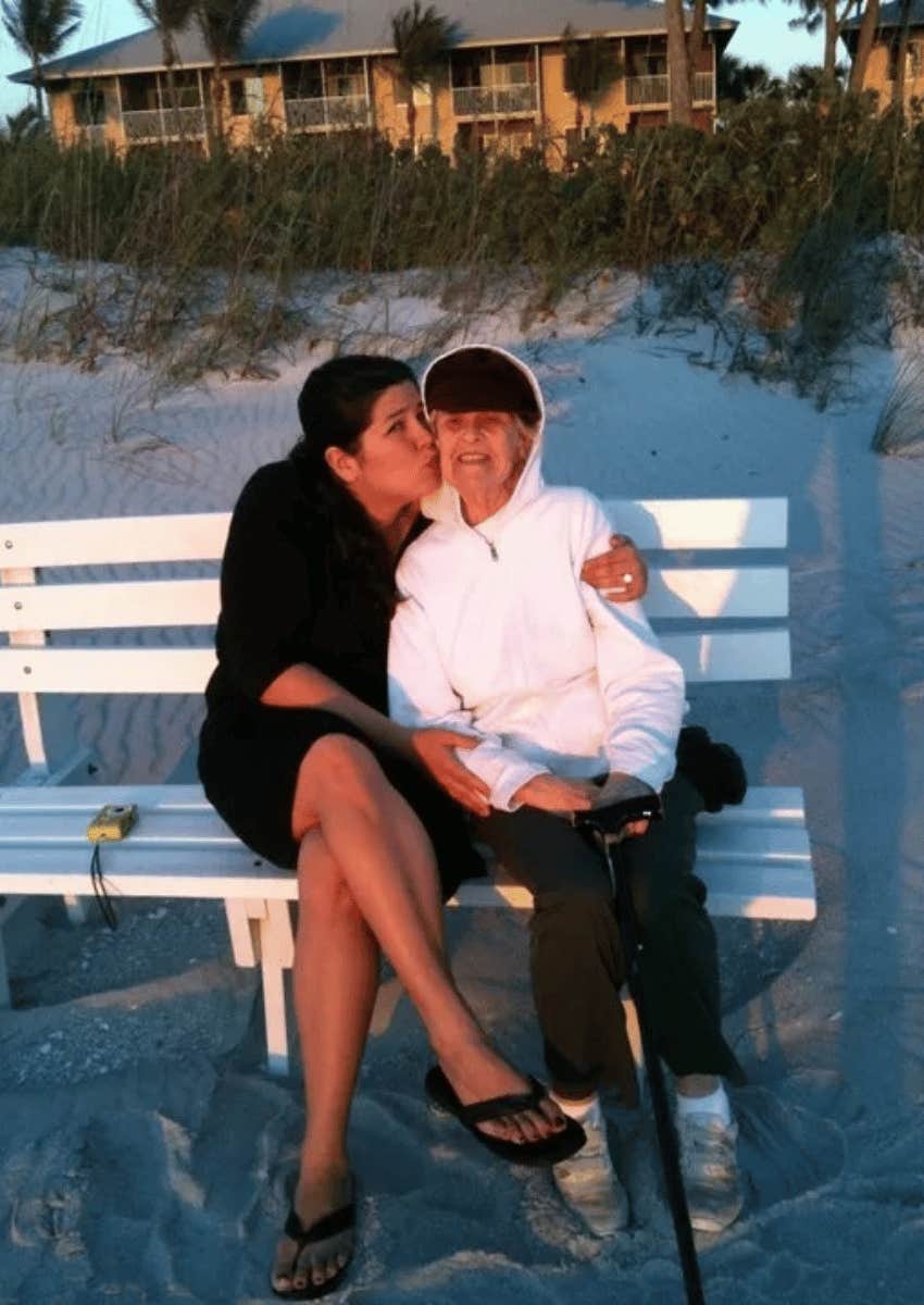 author posing with her mother on a bench on the beach