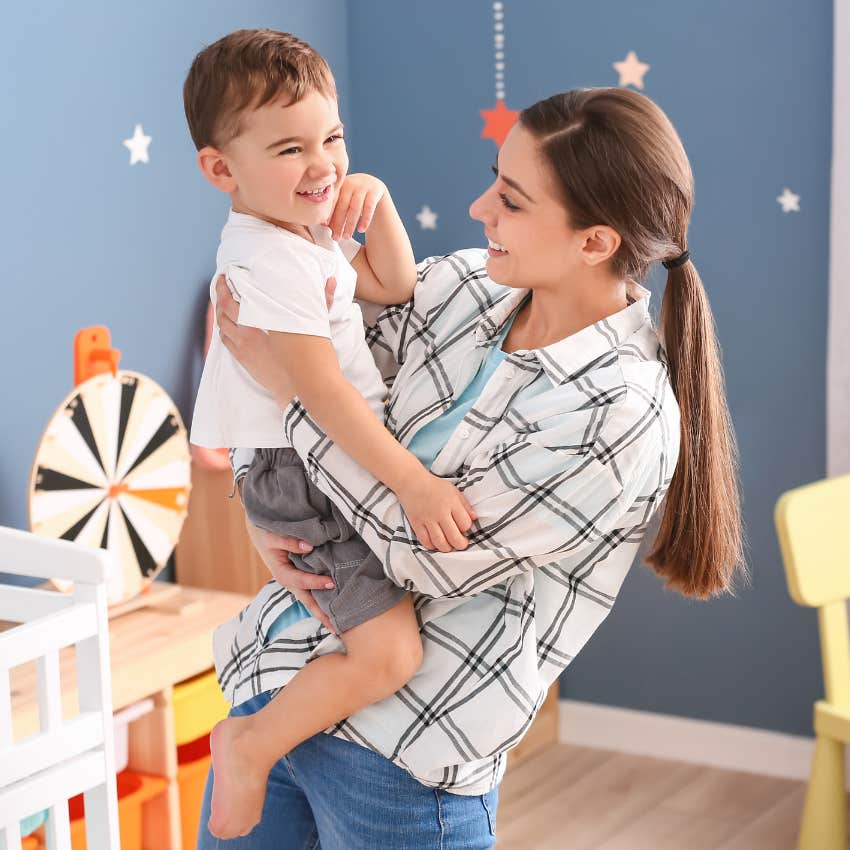 Nanny holding a toddler and smiling. 