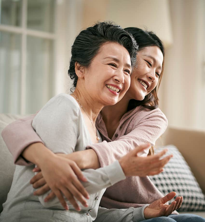 Younger woman hugs. older woman, both smile