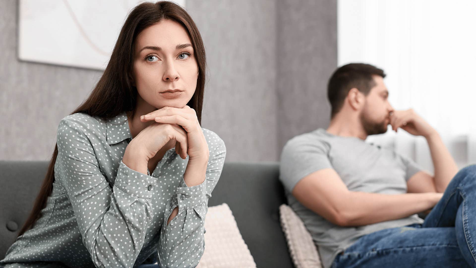 man and woman ignoring each other while sitting on couch