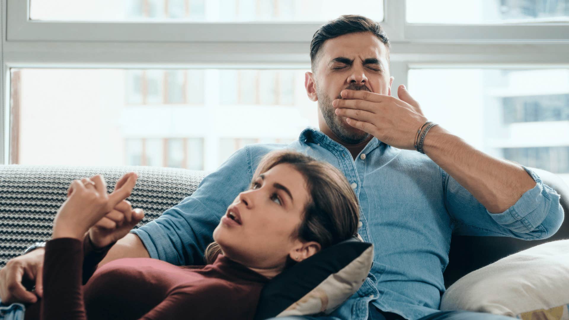 man yawning while woman talks