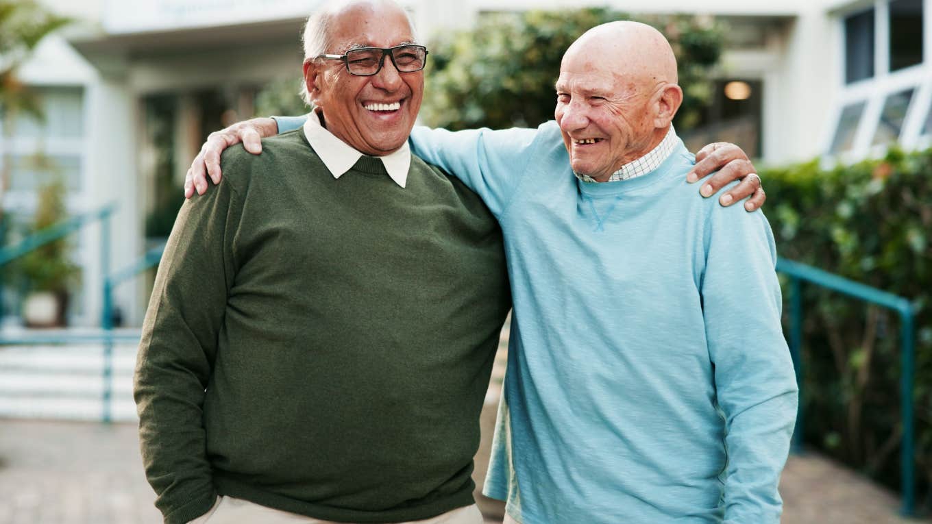 Two older men smiling and hugging each other.