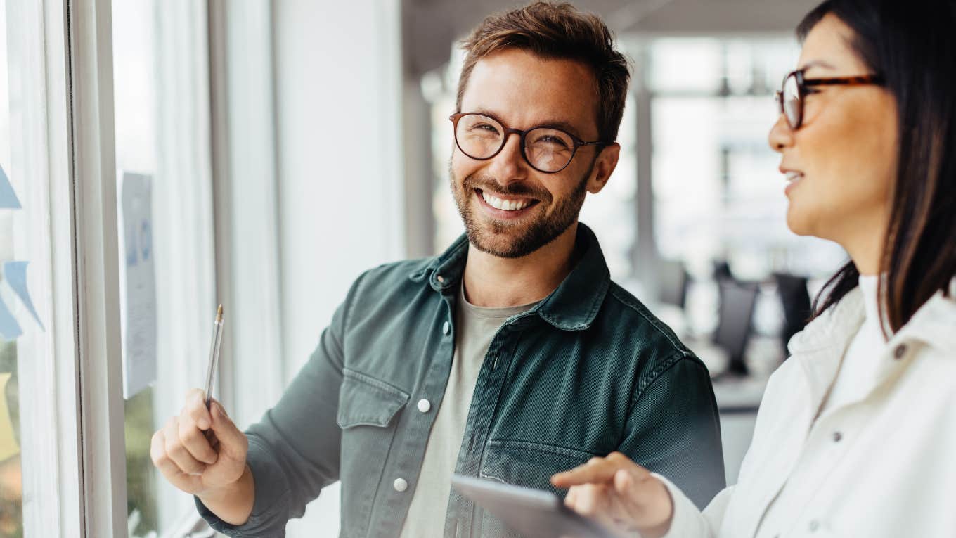 Man smiling and writing on a whiteboard.