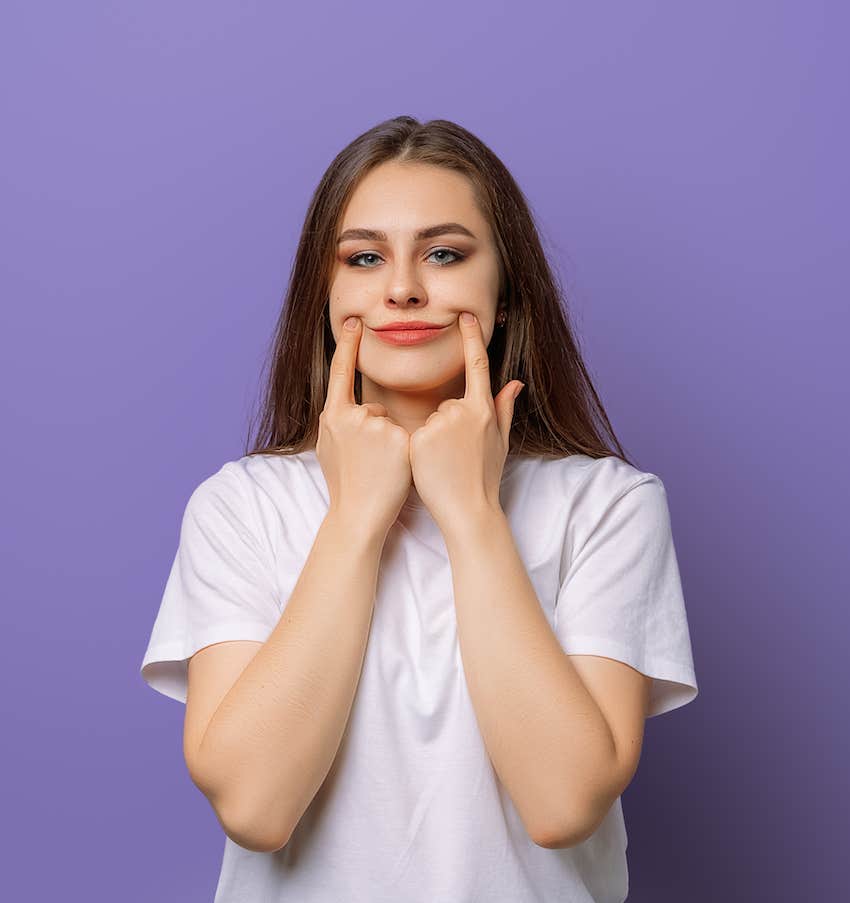 She uses her fingers to push lips into a smile