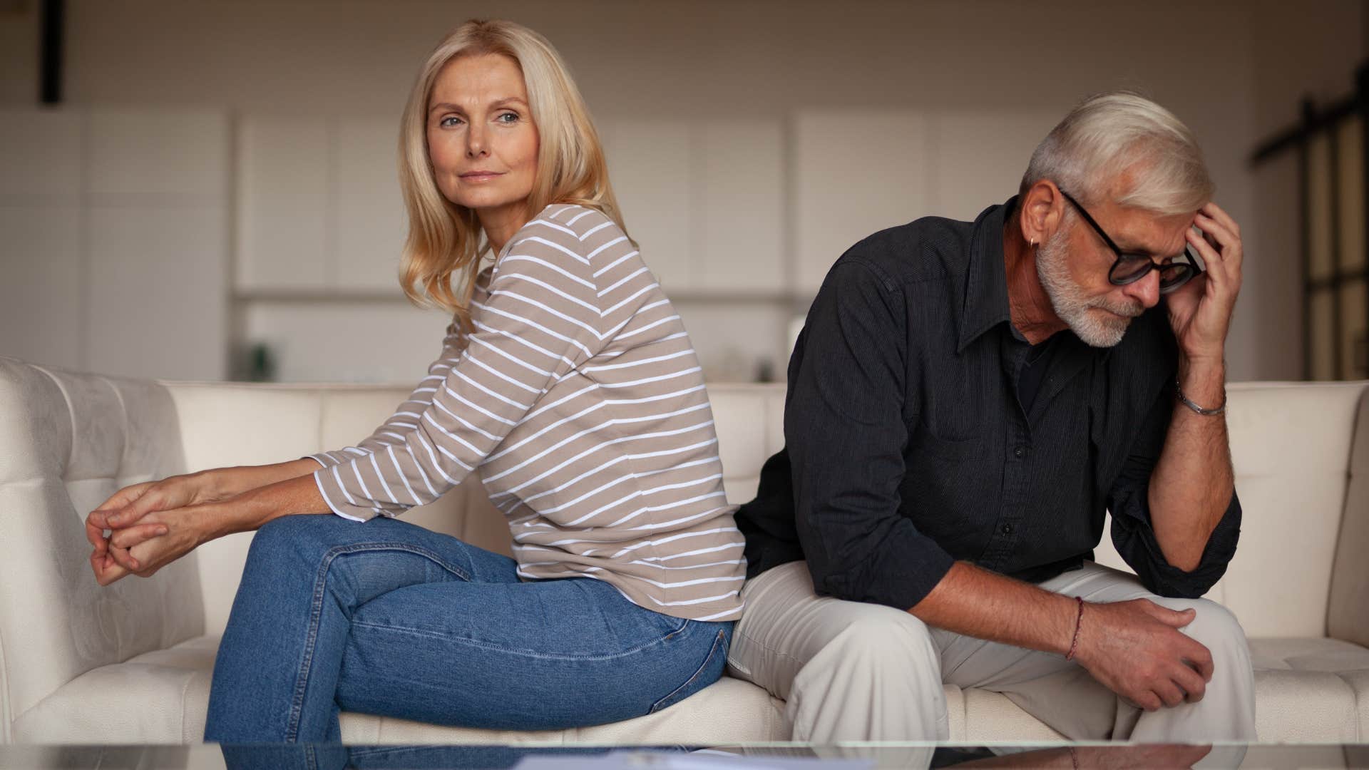 Older couple looking upset sitting together on the couch.