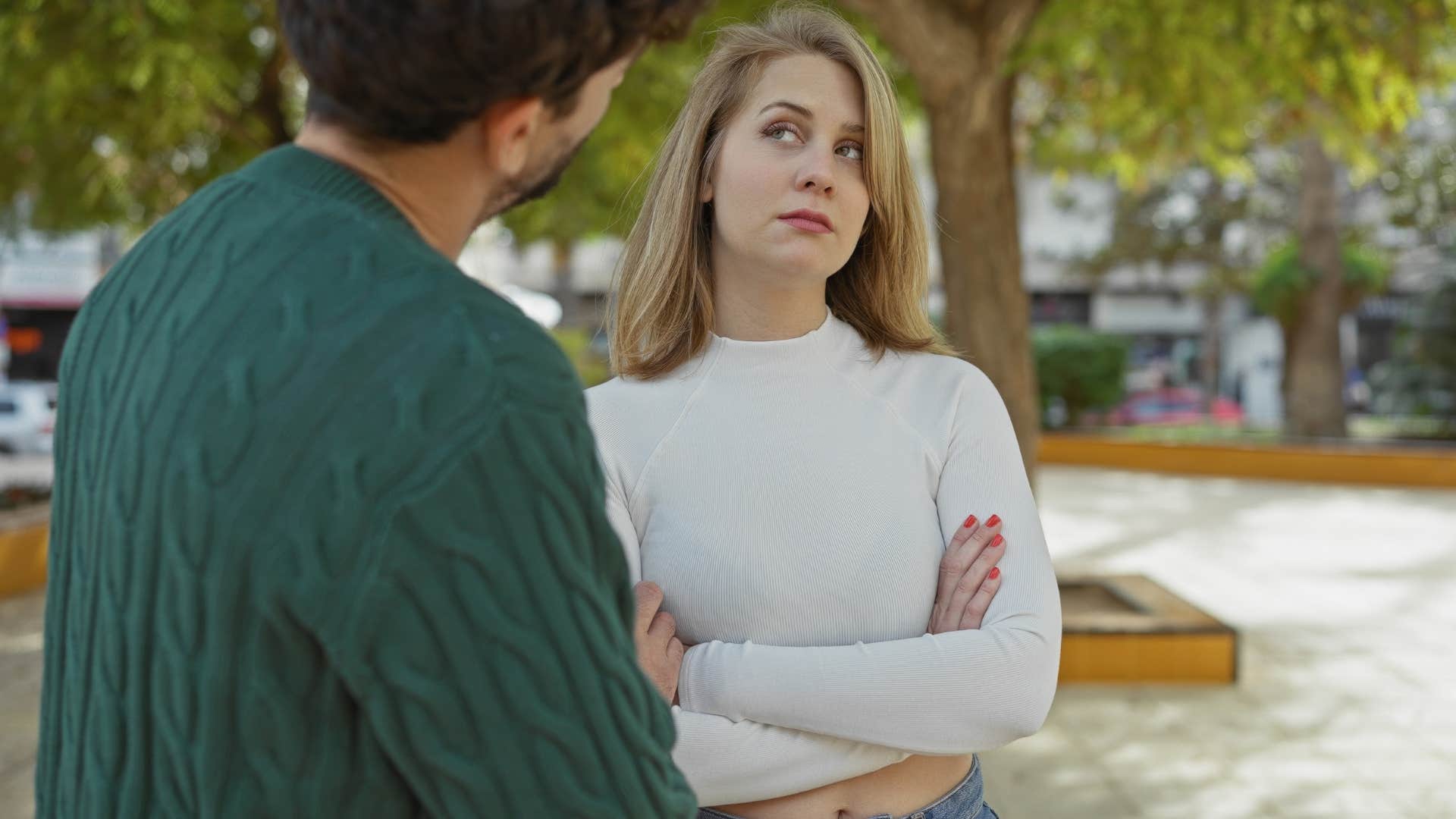 Woman crossing her arms while a man talks to her.