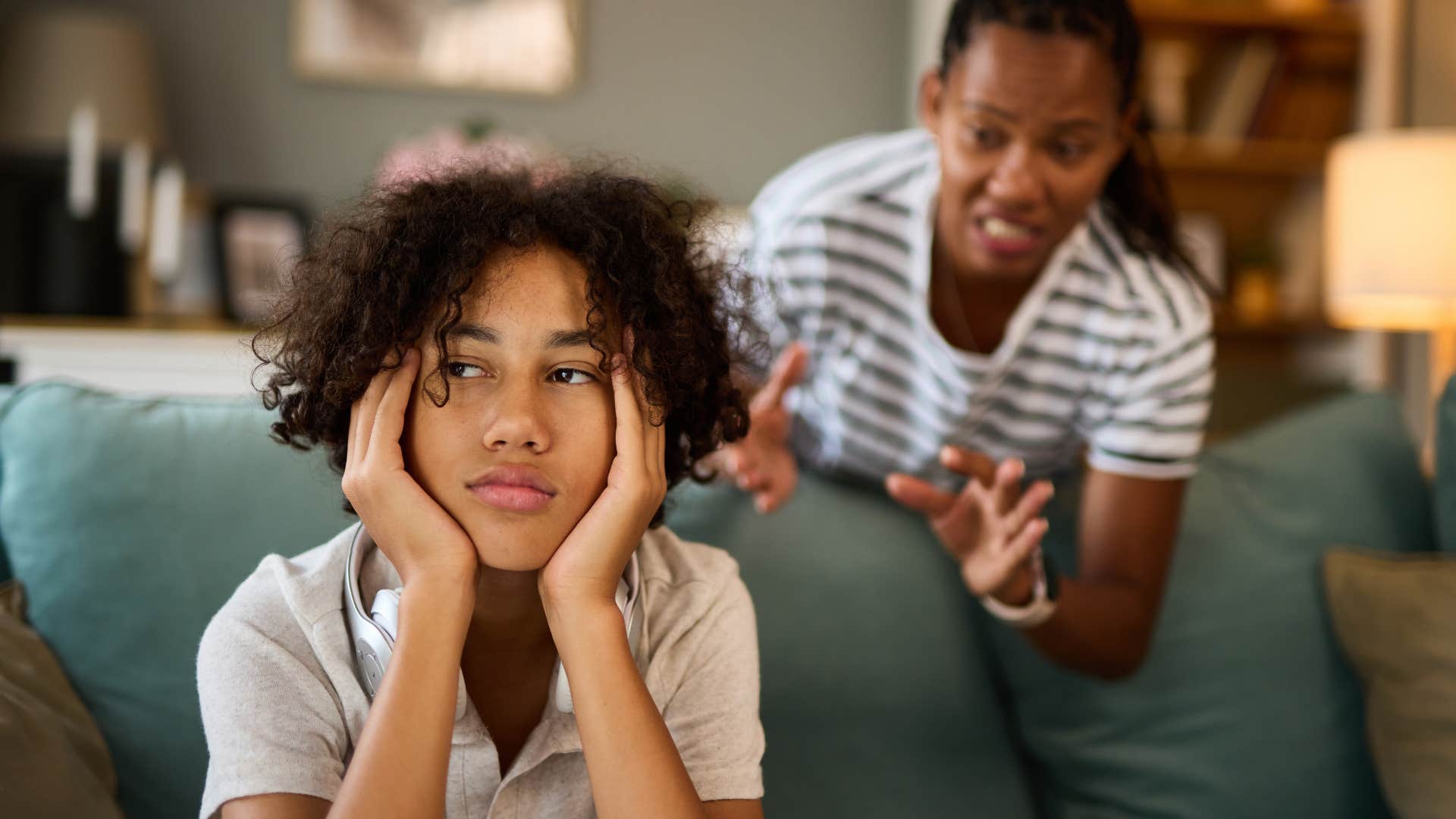 Young man looking sad while his mom talks to him. 