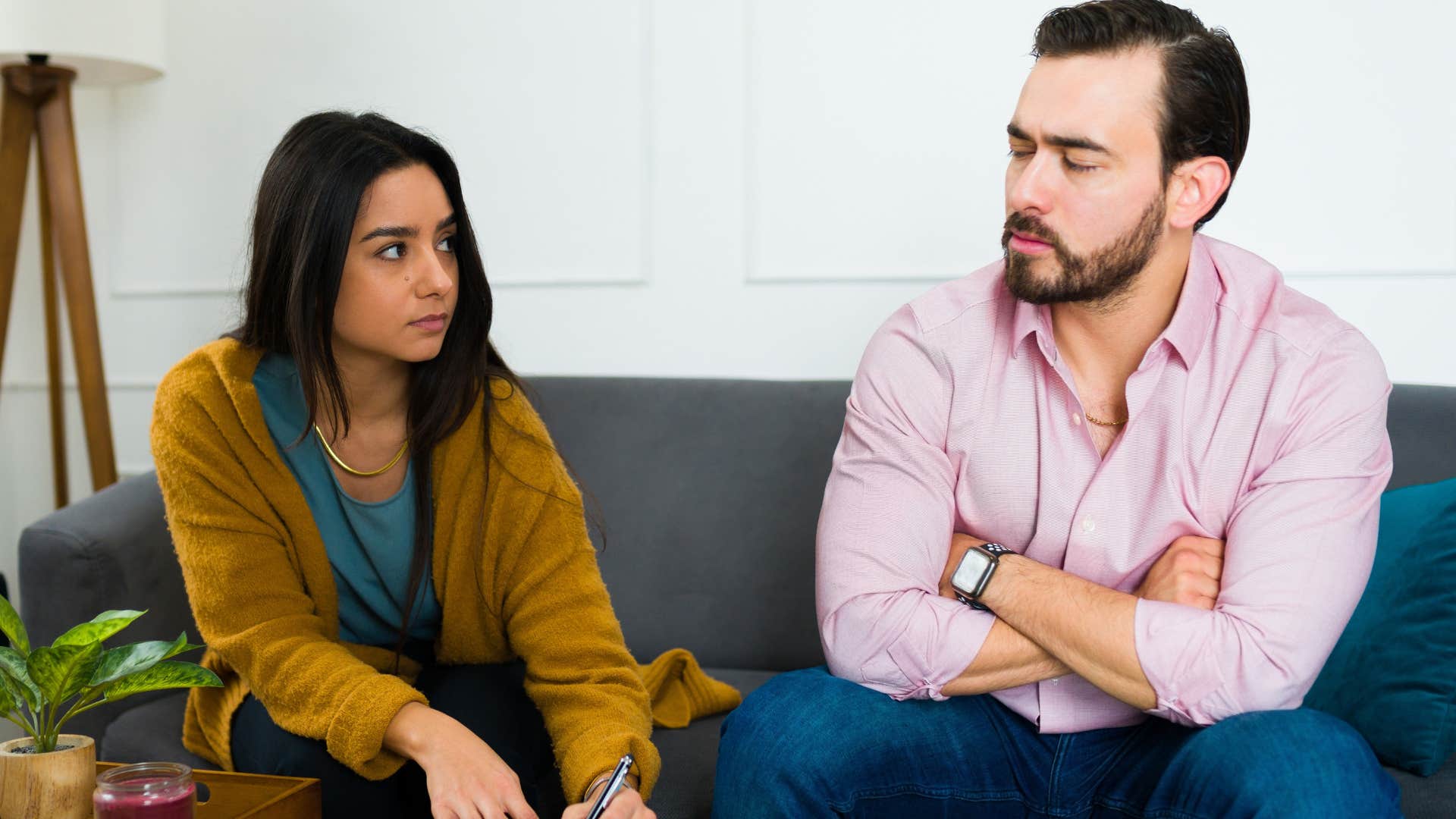 Man and woman sitting on a couch looking annoyed.