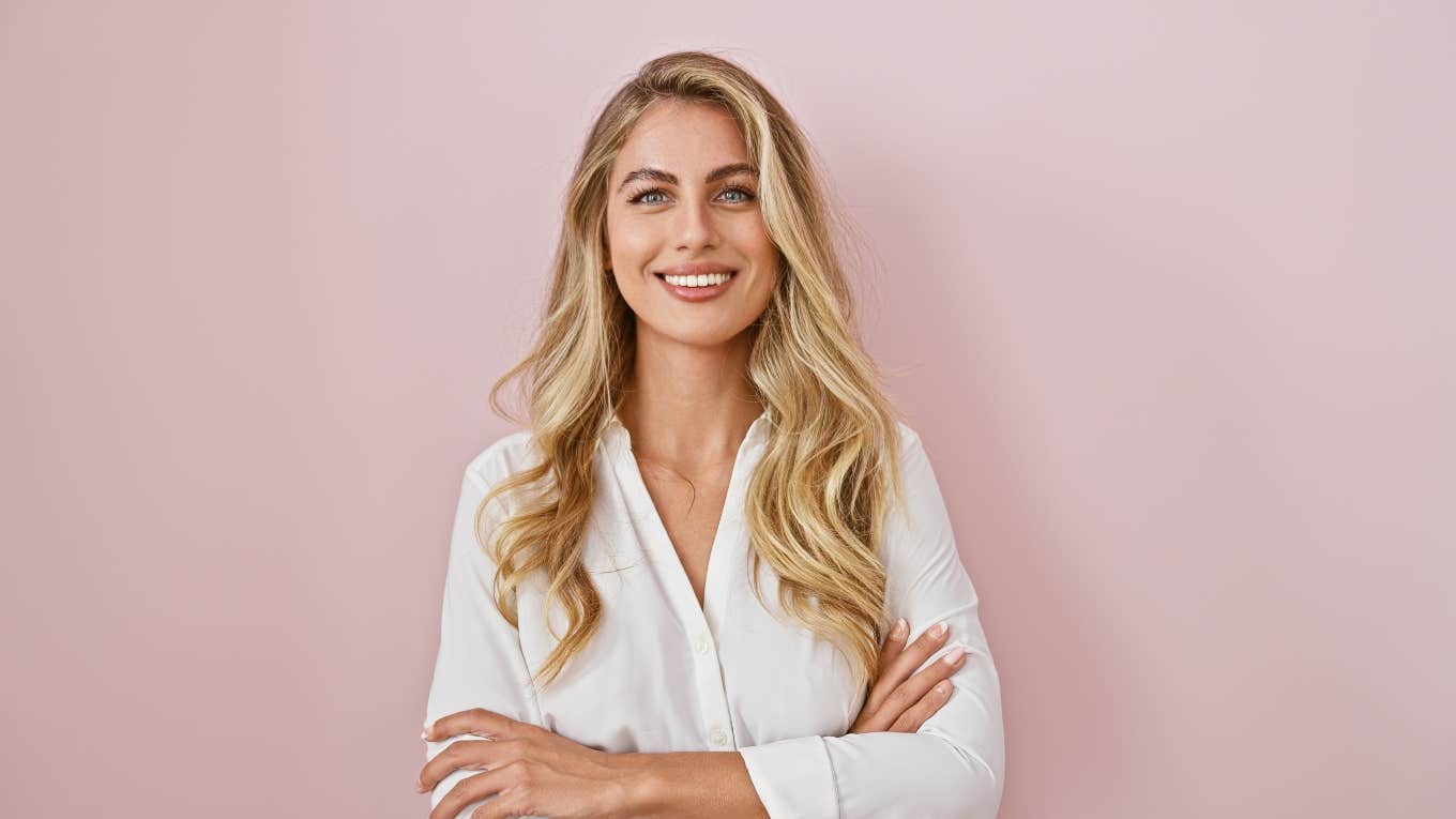 pretty blonde woman standing against pink background