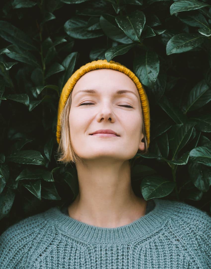 She closes her eyes and relaxes against a leafy hedge