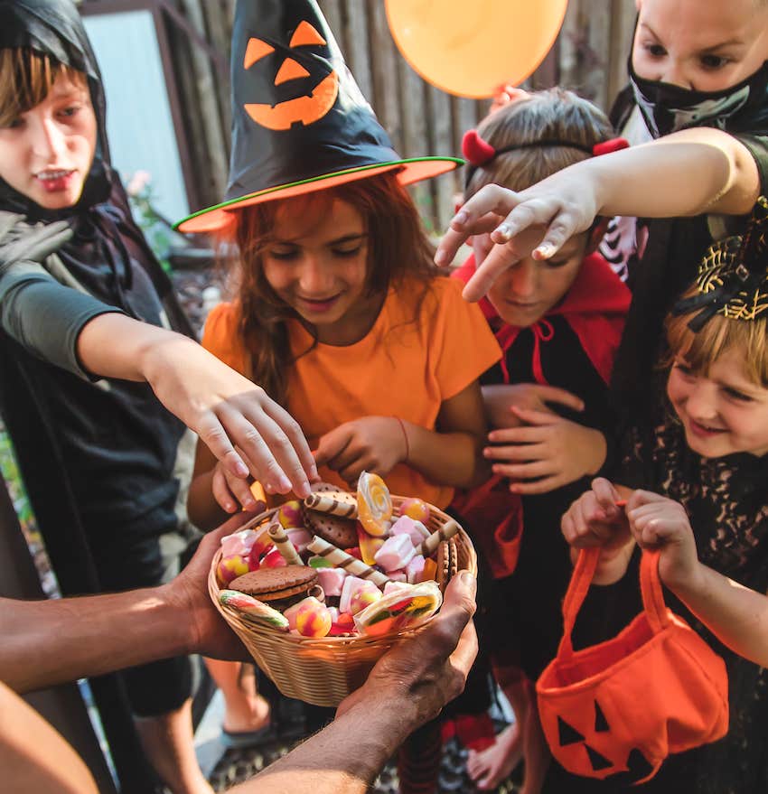 Kids in costume reach for candy in basket