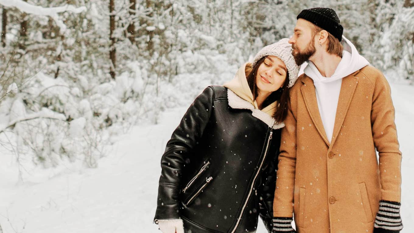 Couple cuddling as they walk in the winter snow.