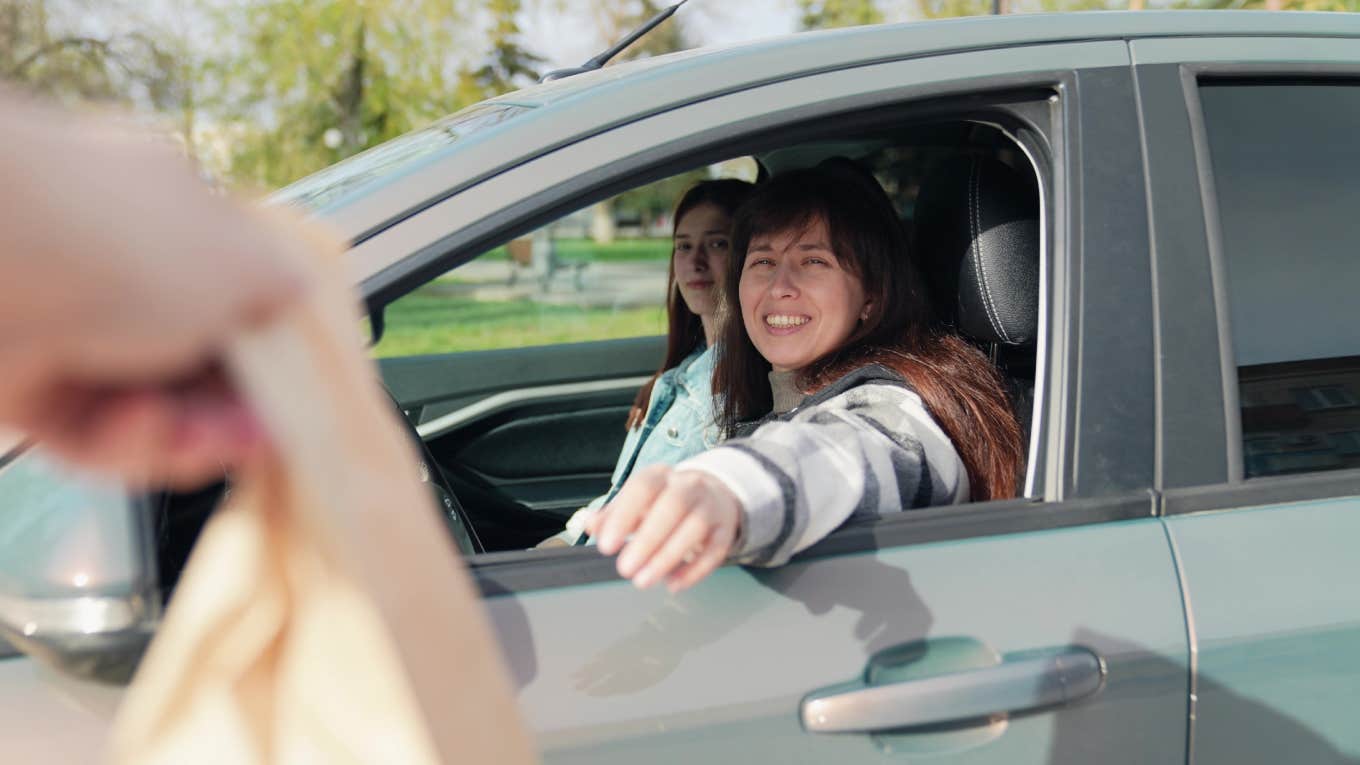 woman in car grabbing food from drive thru