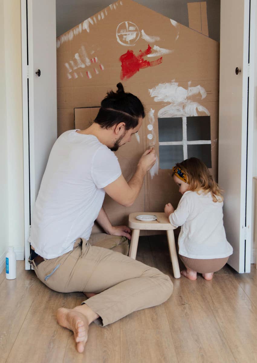 father and daughter painting cardboard house