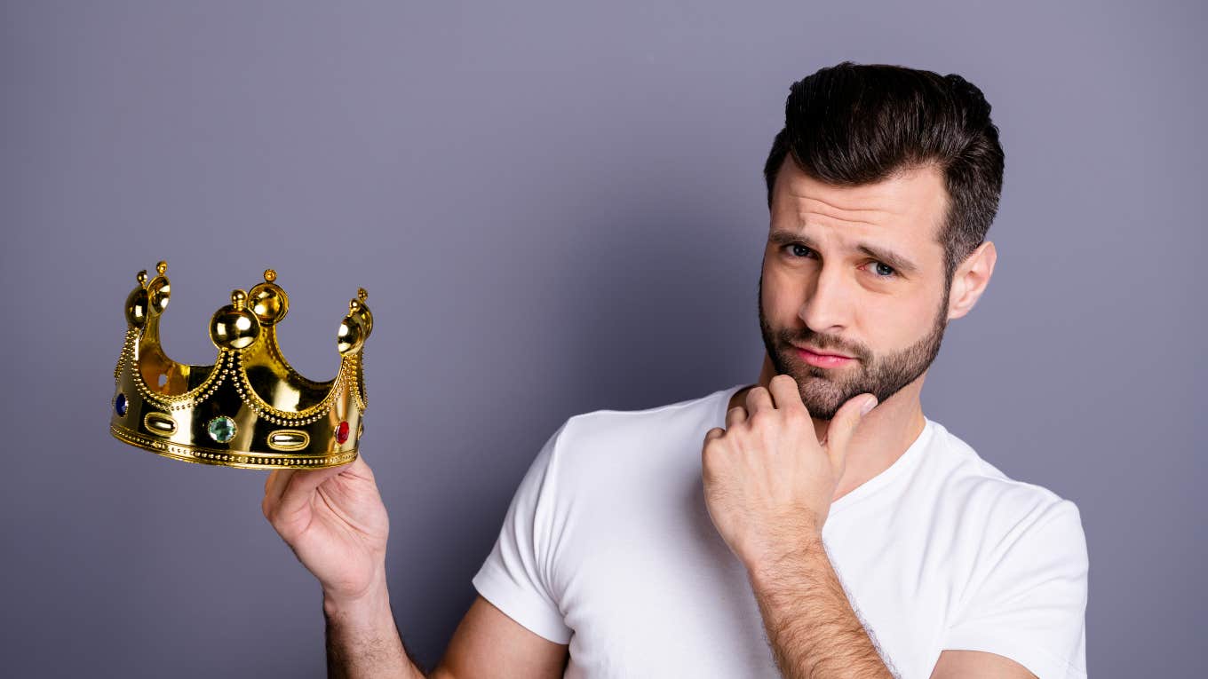 man holding a crown thinking about whether or not to wear it