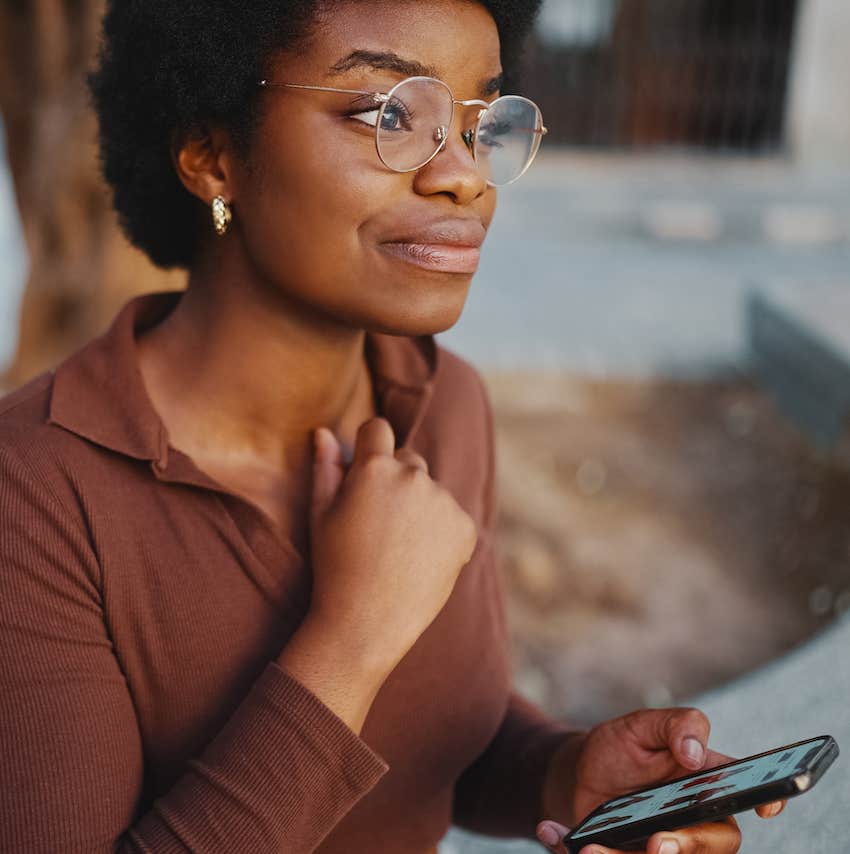 She hold her phone and looks up in thought