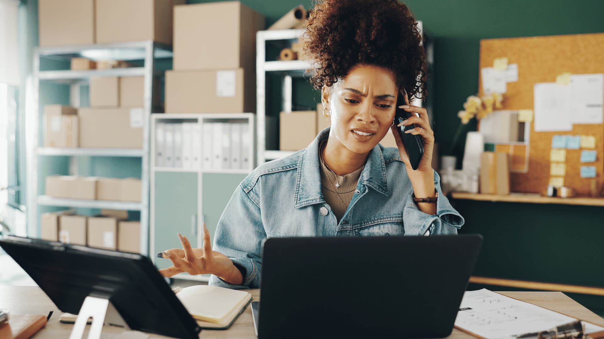 Busy and frustrated woman at desk takes a phone call