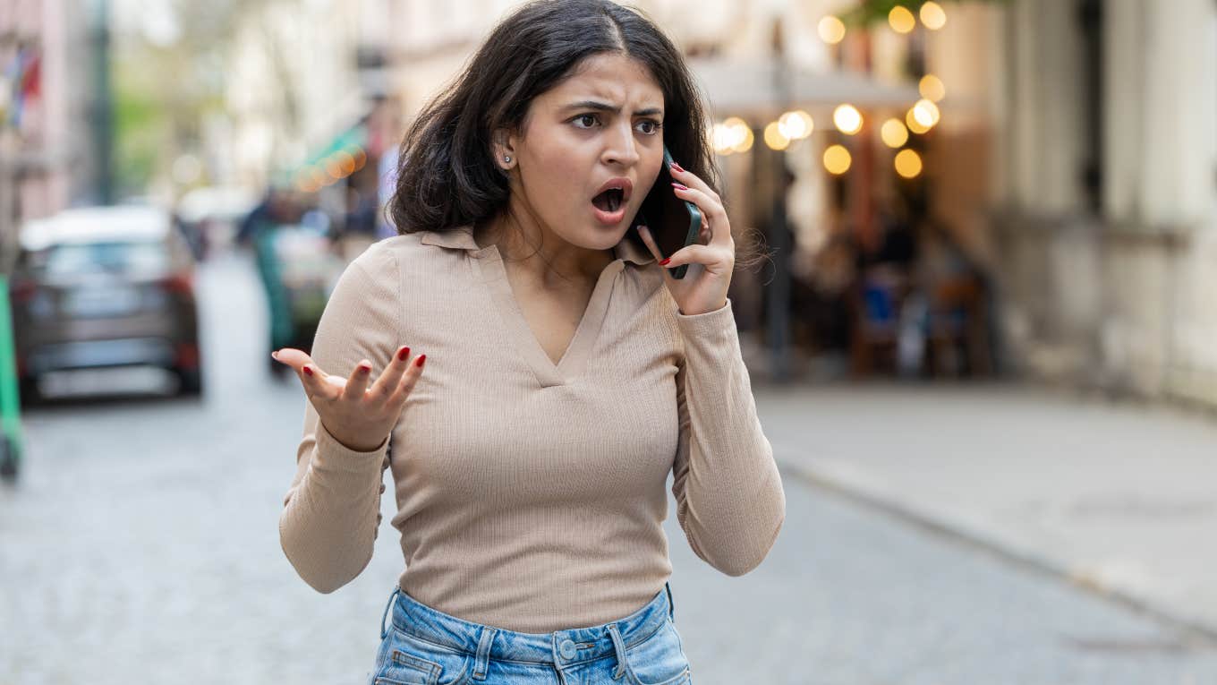 angry woman walking down the street talking on the phone