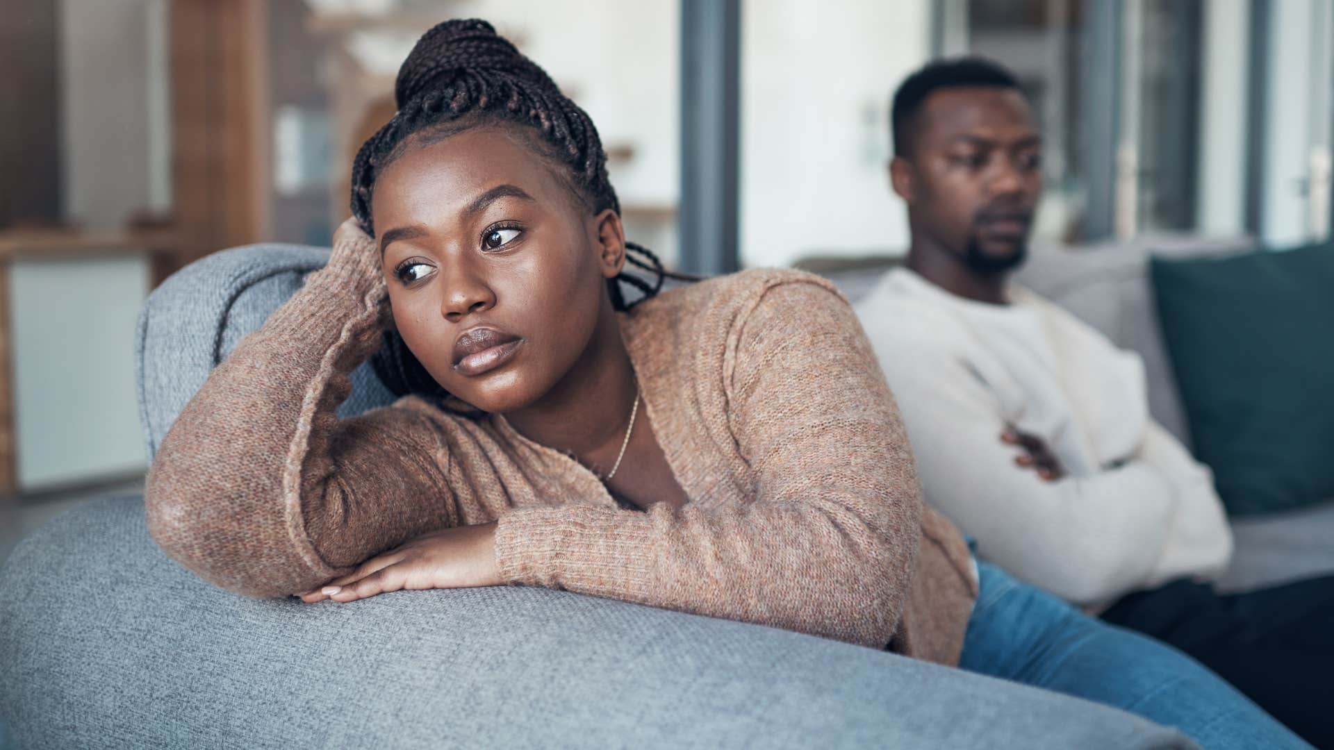 Woman looking upset while her husband sits behind her.