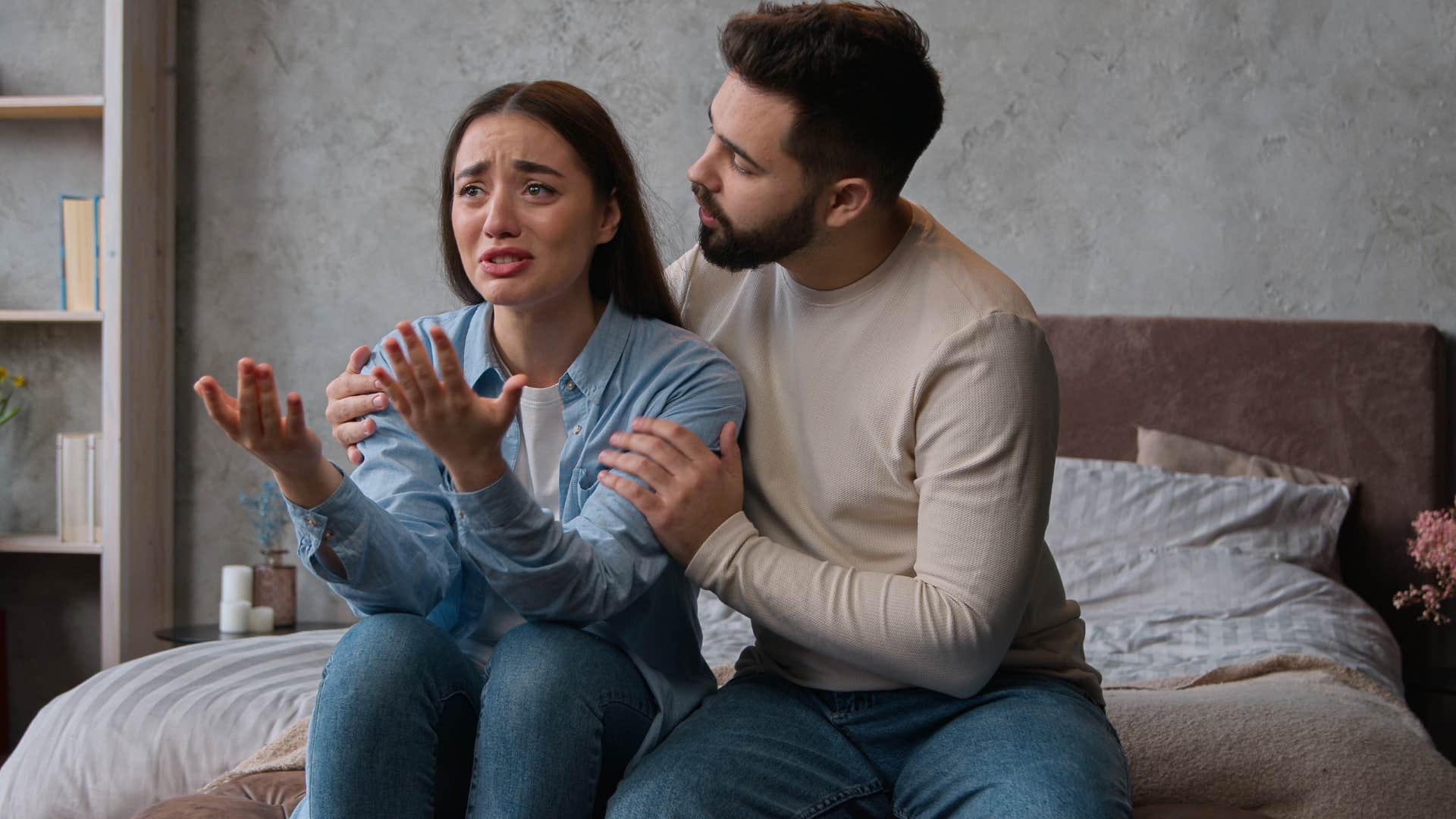 Man comforting his upset wife in their home.