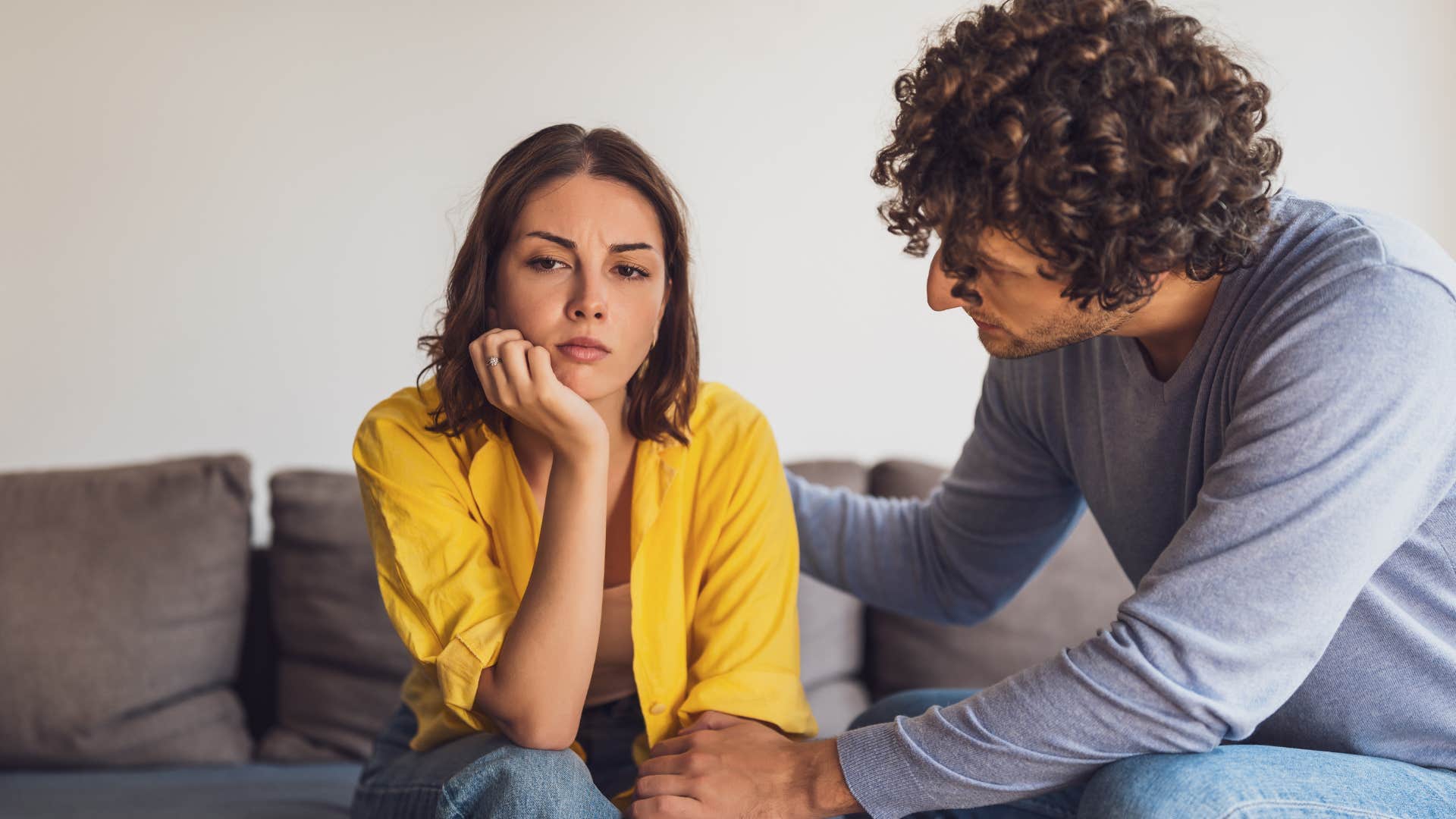 Man comforting his frustrated wife on the couch.