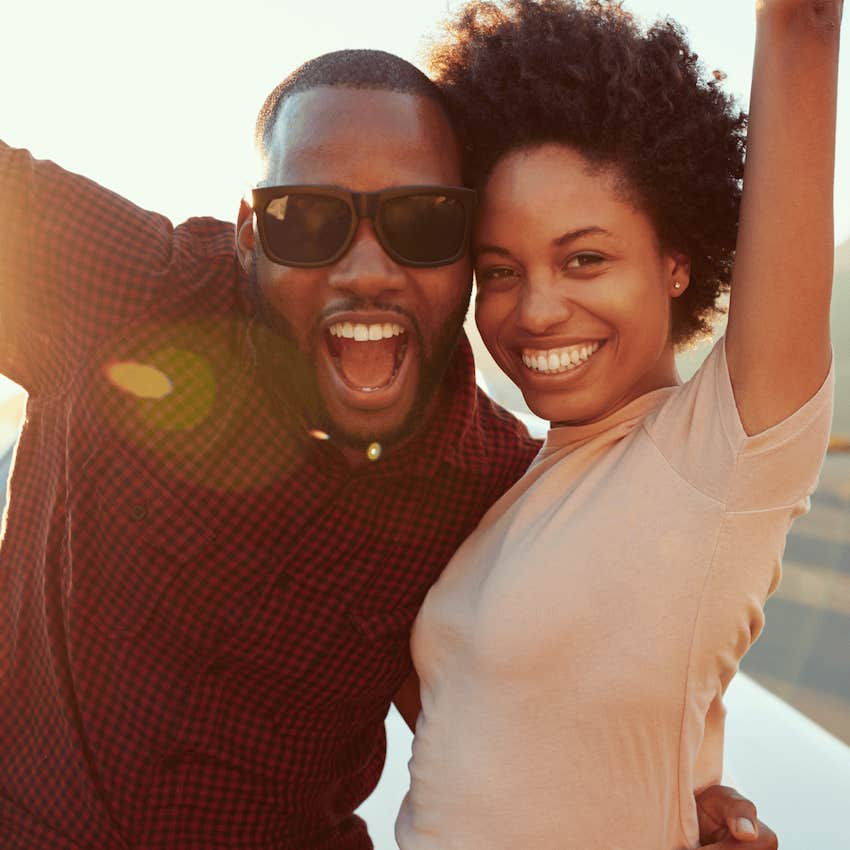 Happy couple raise arms and are on a road trip