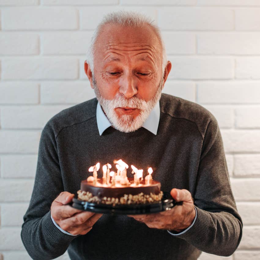 Elderly man blowing out candles on birthday cake