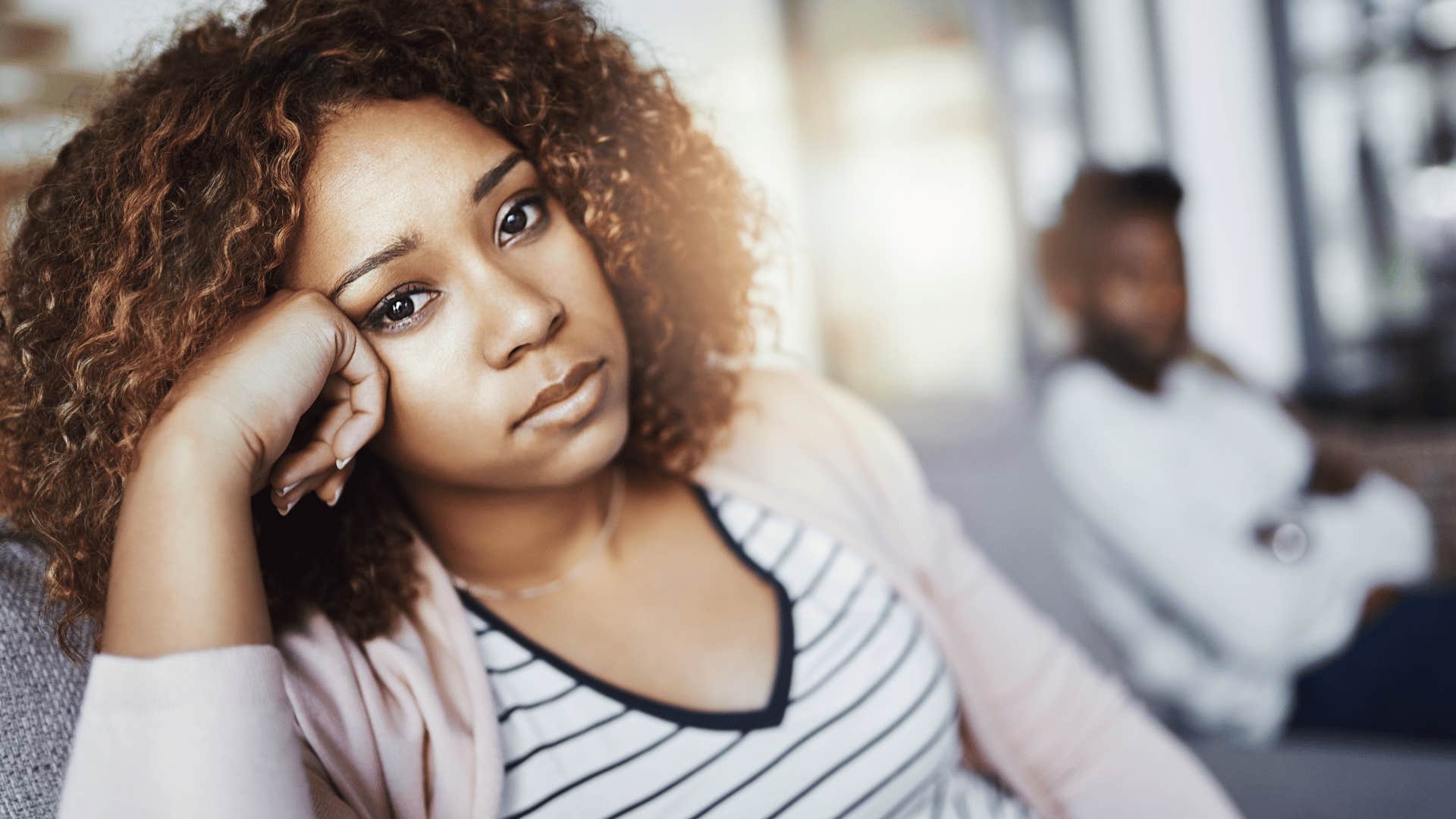 She rest head on her fist while he sits cross armed in background