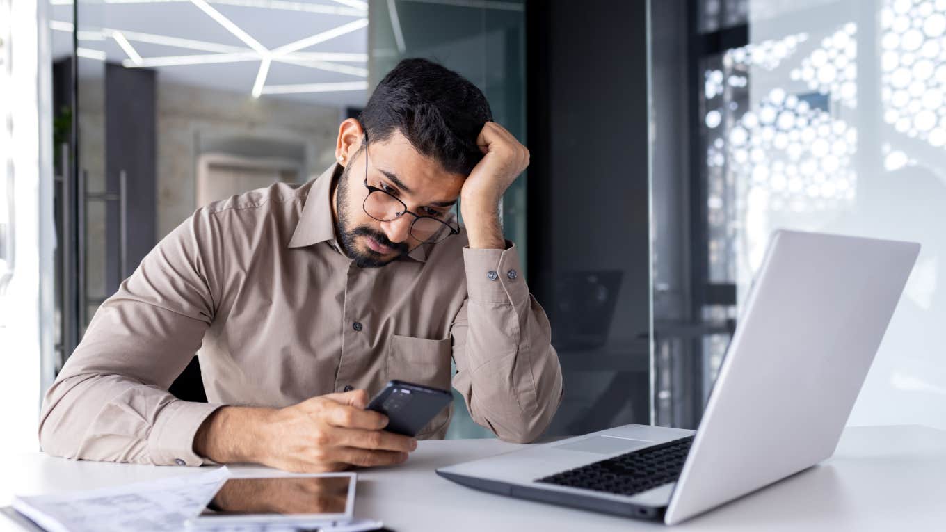 Upset businessman reading news on phone in office