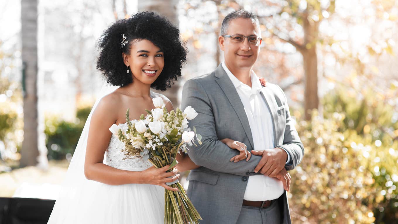 portrait of smiling bride and father arm-in-arm on wedding day