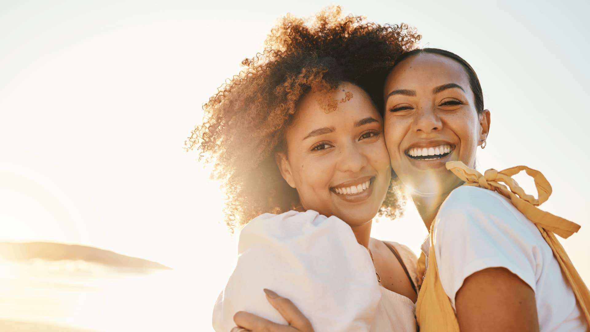 Coouple hugs and smiles with sunlight behind them