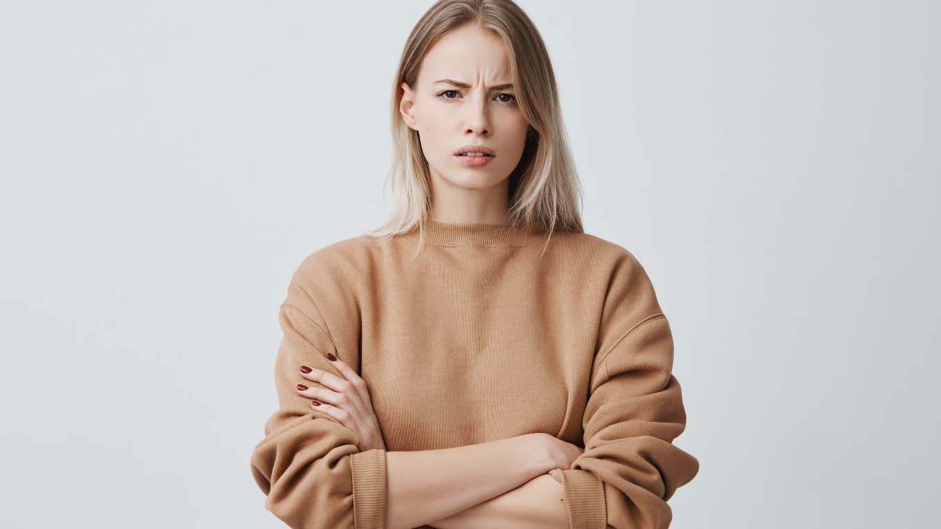 frowning, upset woman in front of gray backdrop