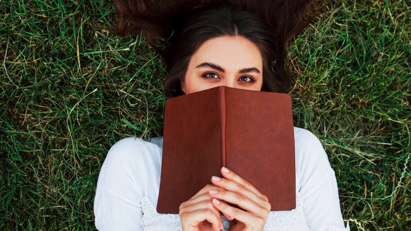 Woman resting with a good book, grounding self in grass.