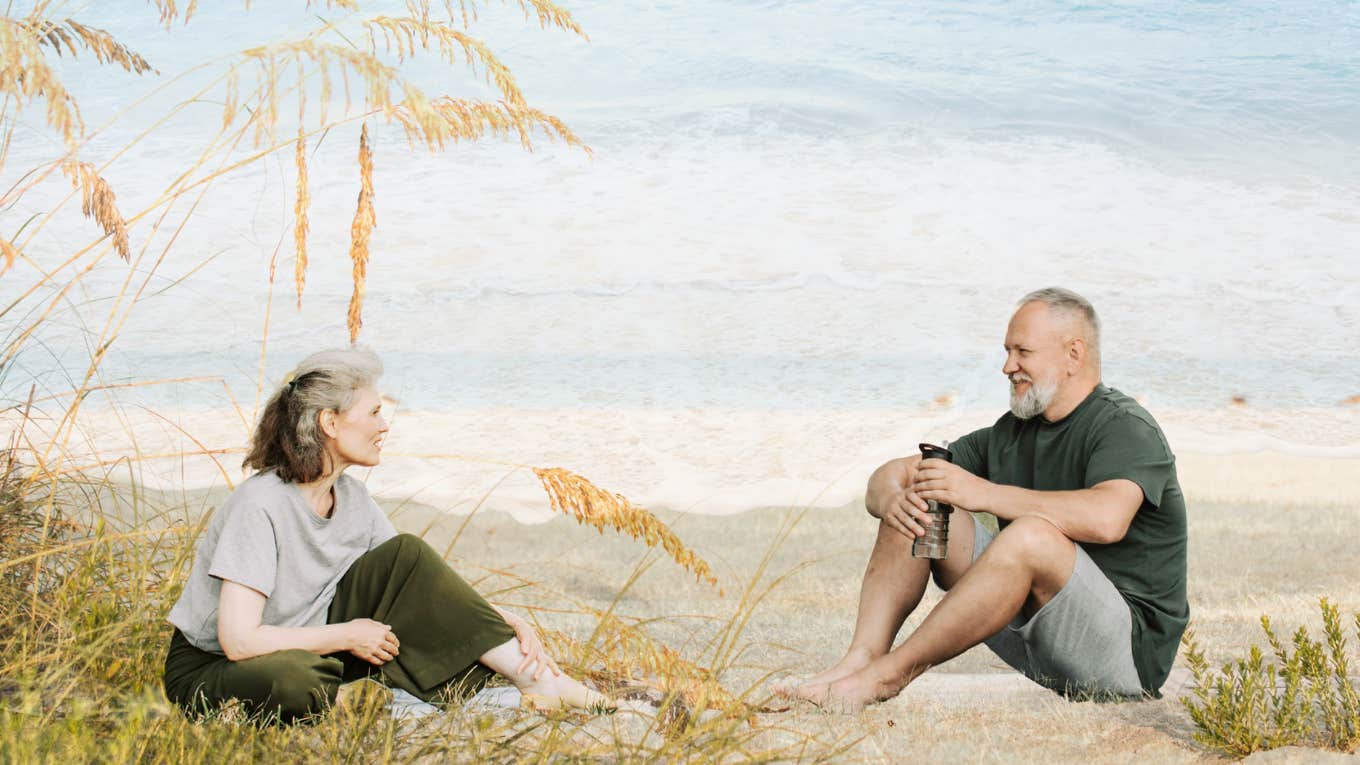 Mature couple, sitting on the beach together.